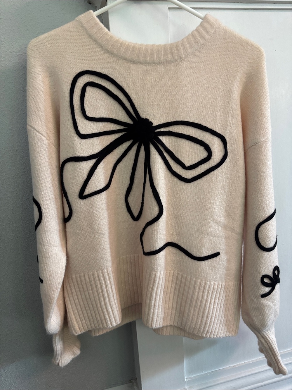 Altar'd State cream knit sweater with bold black 3D embroidered bow on the front